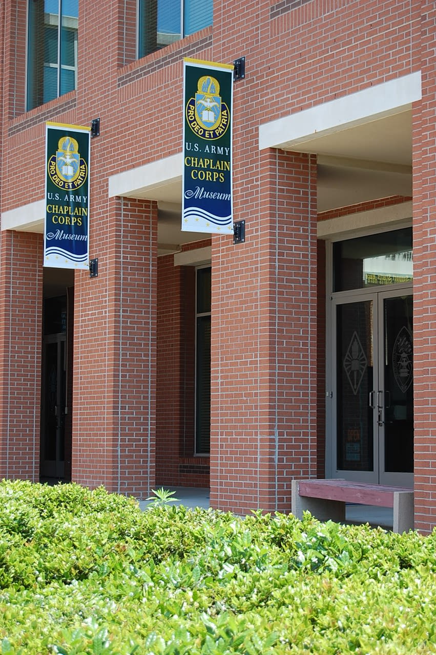 Two signs/banners for the US Army Chaplain Corps Museum outside the main building.